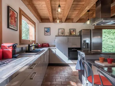 a large kitchen with stainless steel appliances and wooden ceilings at Chalet CLADIE - Private Jacuzzi & Sauna - View of Mont Blanc range - By Cozee Rentals in Les Houches