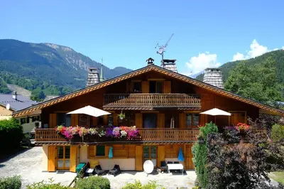 a large wooden house with a balcony with flowers at Appartement Les Clarines in Les Houches
