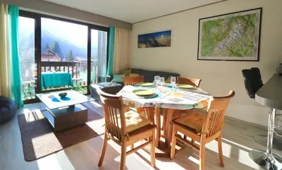 a living room with a table and chairs with a view at Chamonix centre, 51m2, vue Mt Blanc, 2 à 6 pers, 2 balcons in Chamonix-Mont-Blanc