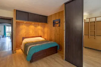 a bedroom with a bed and a wooden wall at Chamonix centre, 51m2, vue Mt Blanc, 2 à 6 pers, 2 balcons in Chamonix-Mont-Blanc