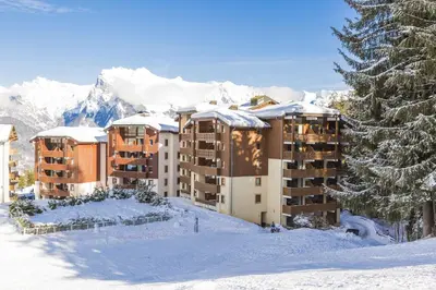 a hotel in the snow with snow covered mountains at Résidence Odalys Le Buet in Morillon
