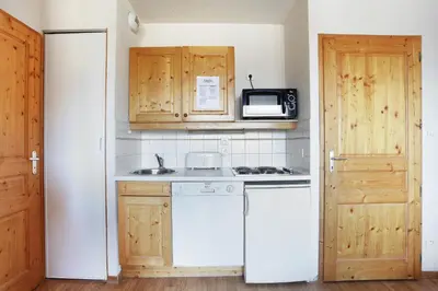 a kitchen with a white refrigerator and a microwave at Résidence Odalys Le Buet in Morillon