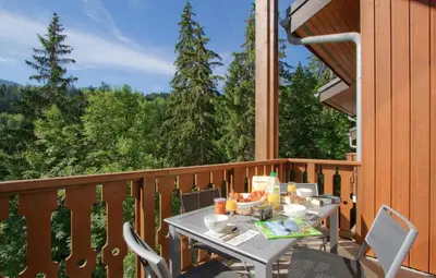 a table on a balcony with a table and chairs at Résidence Odalys Le Buet in Morillon
