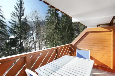 a balcony with a table and a laptop on it at Résidence Odalys Le Buet in Morillon