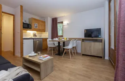 a living room with a kitchen and a table in a room at Résidence Odalys Le Buet in Morillon