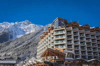 a large hotel with a mountain in the background at Alpina Eclectic Hotel in Chamonix-Mont-Blanc