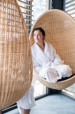 a woman wrapped in a towel sitting in a wicker chair at Alpina Eclectic Hotel in Chamonix-Mont-Blanc