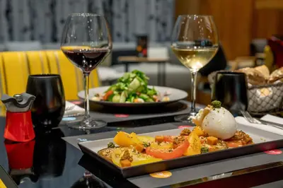 a table with a plate of food and two glasses of wine at Alpina Eclectic Hotel in Chamonix-Mont-Blanc