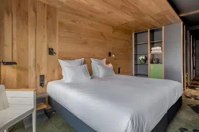 a bedroom with a large white bed and wooden walls at Alpina Eclectic Hotel in Chamonix-Mont-Blanc