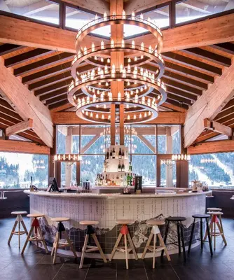 a large chandelier hangs above a bar in a lodge at Alpina Eclectic Hotel in Chamonix-Mont-Blanc