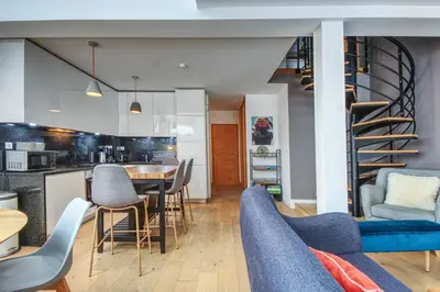 a living room with a table and chairs and a spiral staircase at Maison Des Praz Chamonix in Chamonix-Mont-Blanc