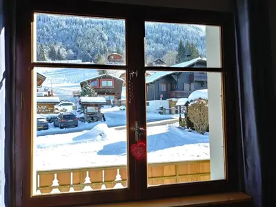 a window with a view of a snow covered yard at Le Si-près Pied des pistes in Les Carroz d'Araches