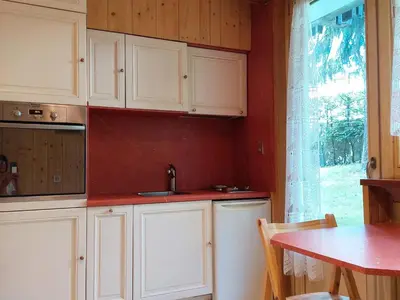 a kitchen with white cabinets and a table and a window at Studio rénové 16m2, terrasse, animaux admis, parking, près télécabine Brévent - FR-1-517-3 in Chamonix-Mont-Blanc