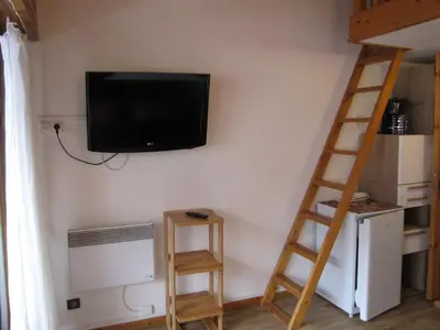 a room with a television on a wall with two wooden ladders at Appartement à Chamonix avec Balcon, Animaux Acceptés et Parking - FR-1-517-12 in Chamonix-Mont-Blanc