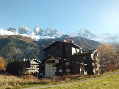 a house on a hill with mountains in the background at Appartement à Chamonix avec Balcon, Animaux Acceptés et Parking - FR-1-517-12 in Chamonix-Mont-Blanc