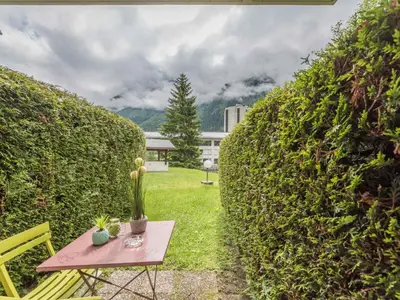 a picnic table in a garden with a hedge at Studio cosy à Chamonix - Animaux admis, parking privé - FR-1-517-21 in Chamonix-Mont-Blanc