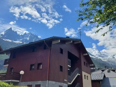a red building with snow capped mountains in the background at Studio cosy à Chamonix - Animaux admis, parking privé - FR-1-517-21 in Chamonix-Mont-Blanc