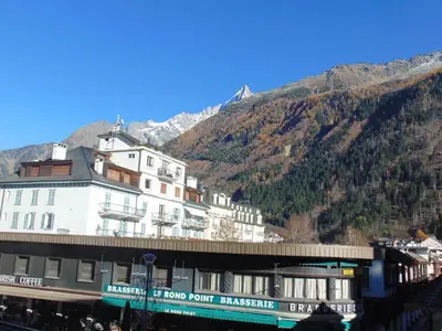 a large white building with a mountain in the background at Studio convivial en zone piétonne avec animaux admis, balcon - Chamonix - FR-1-517-23 in Chamonix-Mont-Blanc