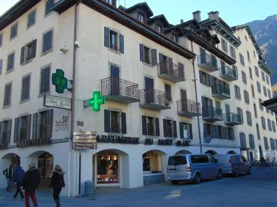 a large white building with a green cross on it at Studio convivial en zone piétonne avec animaux admis, balcon - Chamonix - FR-1-517-23 in Chamonix-Mont-Blanc