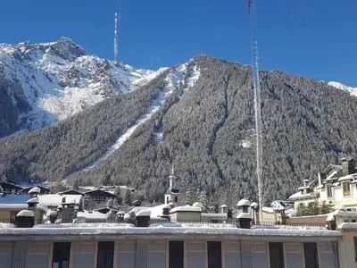a building in front of a mountain with snow on it at Magnifique appartement centre-ville - Animaux admis, WiFi - FR-1-517-37 in Chamonix-Mont-Blanc