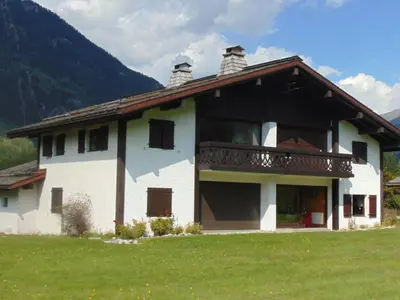 a large white house with a balcony on a field at Charmant 3 pièces avec terrasse, parking, 6 couchages - Chamonix - FR-1-517-38 in Chamonix-Mont-Blanc