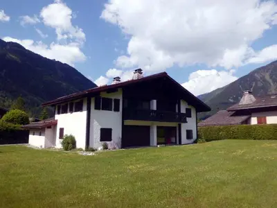 a house in a field with mountains in the background at Charmant 3 pièces avec terrasse, parking, 6 couchages - Chamonix - FR-1-517-38 in Chamonix-Mont-Blanc