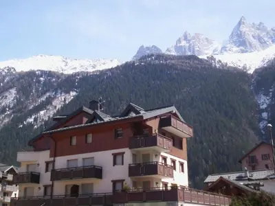 a building with snow covered mountains in the background at Charmant 2 Pièces Central avec Terrasse - Chamonix - FR-1-517-41 in Chamonix-Mont-Blanc