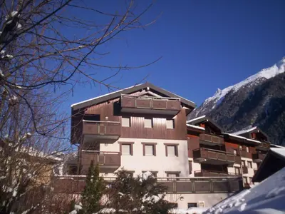 a building in front of a snowy mountain at Charmant 2 Pièces Central avec Terrasse - Chamonix - FR-1-517-41 in Chamonix-Mont-Blanc
