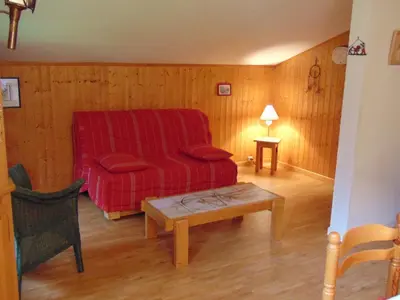 a living room with a red couch and a table at Bel appartement rénové à Chamonix avec vue sur le Mont-Blanc, parking et animaux admis - FR-1-517-51 in Chamonix-Mont-Blanc