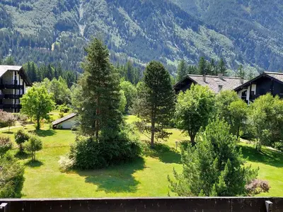 a green yard with trees and houses and mountains at Bel appartement rénové à Chamonix avec vue sur le Mont-Blanc, parking et animaux admis - FR-1-517-51 in Chamonix-Mont-Blanc