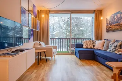 a living room with a blue couch and a large window at Apartment Arve - Chamonix Peaks Retreat in Chamonix-Mont-Blanc