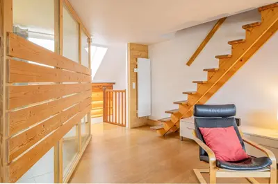 a room with wooden stairs and a chair at Apartment Genevrier - Spacious Balcony with Mont Blanc Views in Chamonix-Mont-Blanc