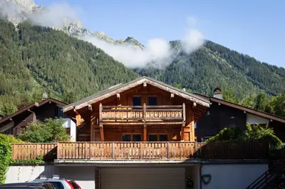 a log cabin with a balcony and a car parked in front at Chalet La Chaumière in Chamonix-Mont-Blanc