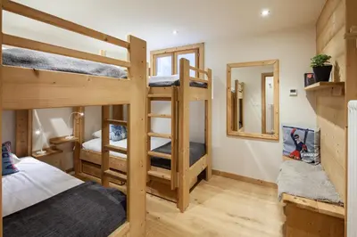 a room with three bunk beds and a mirror at Chalet La Chaumière in Chamonix-Mont-Blanc