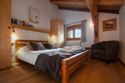 a bedroom with a large bed and a chair at Appartement Clusettes - Happy Rentals in Chamonix-Mont-Blanc