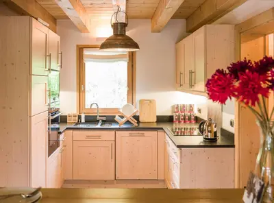 a kitchen with wooden cabinets and a vase with red flowers at Les Chalets des Liarets in Chamonix-Mont-Blanc