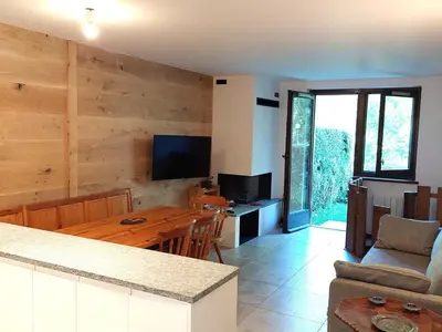 a kitchen and living room with a wooden wall at Superbe 3 pièces Chamonix - Jardin privé - Parking - Animaux admis - FR-1-517-25 in Chamonix-Mont-Blanc