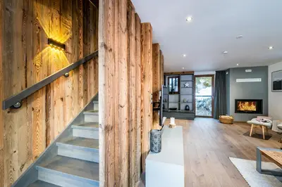 a living room with a wooden wall and stairs at Le Globe Argentière Chamonix - by EMERALD STAY in Chamonix-Mont-Blanc