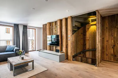 a living room with a couch and a tv and wooden walls at Le Globe Argentière Chamonix - by EMERALD STAY in Chamonix-Mont-Blanc