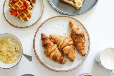 a table topped with plates of croissants and waffles at Le Globe Argentière Chamonix - by EMERALD STAY in Chamonix-Mont-Blanc