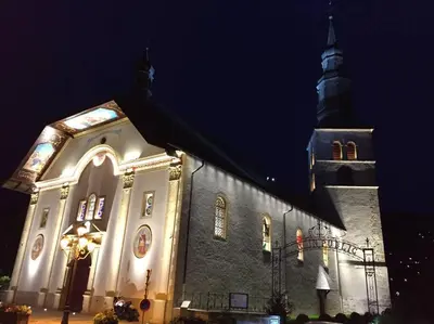 a large church with a clock tower at night at Mont Blanc Residence in Saint-Gervais-les-Bains