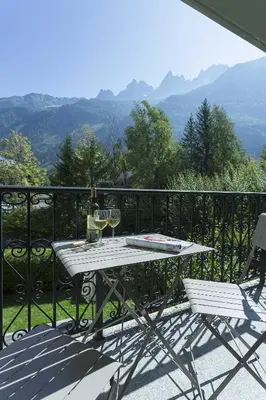 a table and chairs on a balcony with a view of mountains at APARTMENT ENSA - Alpes Travel - Central Chamonix - Sleeps 4 in Chamonix-Mont-Blanc