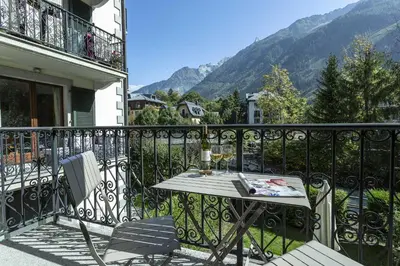 a table and chairs on a balcony with mountains at APARTMENT ENSA - Alpes Travel - Central Chamonix - Sleeps 4 in Chamonix-Mont-Blanc
