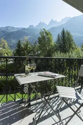 a white table and chairs on a balcony with mountains at APARTMENT ENSA - Alpes Travel - Central Chamonix - Sleeps 4 in Chamonix-Mont-Blanc
