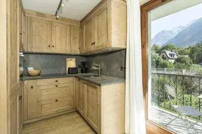 a kitchen with wooden cabinets and a large window at APARTMENT ENSA - Alpes Travel - Central Chamonix - Sleeps 4 in Chamonix-Mont-Blanc