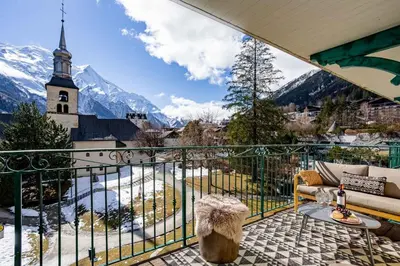 a balcony with a view of a church and mountains at Le Panoramic Mont Blanc Apartment - Chamonix All Year in Chamonix-Mont-Blanc