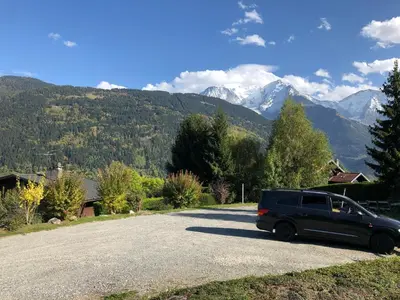 a black van parked on the side of a road with mountains at Le petit Chamois in Saint-Gervais-les-Bains