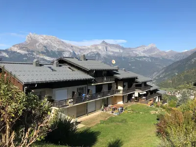 a house on a hill with mountains in the background at Le petit Chamois in Saint-Gervais-les-Bains