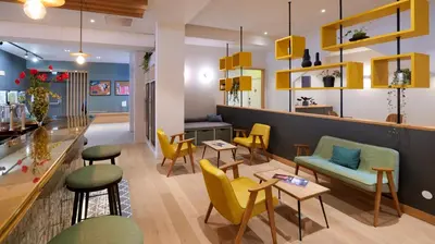 a restaurant with yellow and green chairs and a counter at PlanB Hotel - Living Chamonix in Chamonix-Mont-Blanc