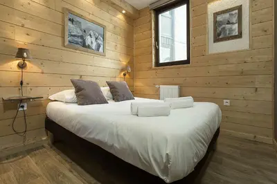 a bedroom with a large bed with wooden walls at APARTMENT BEAUSITE - Alpes Travel - Central Chamonix - Sleeps 2-4 in Chamonix-Mont-Blanc